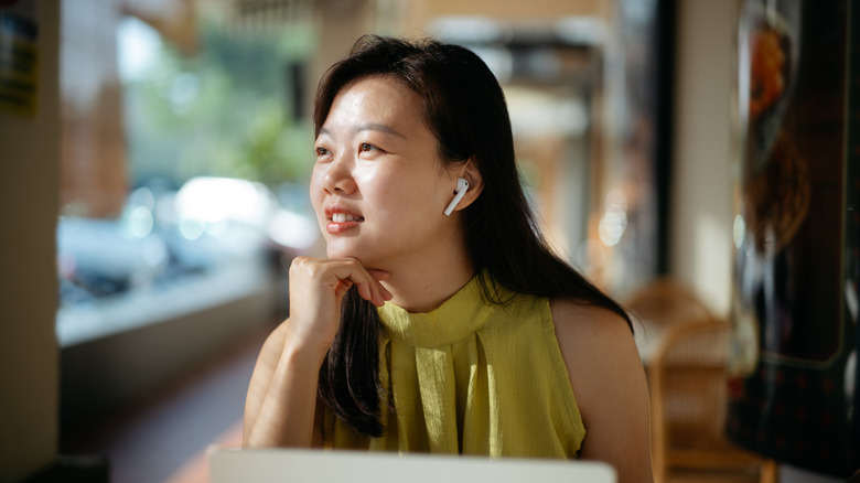 A woman wearing AirPods in a coffee shop