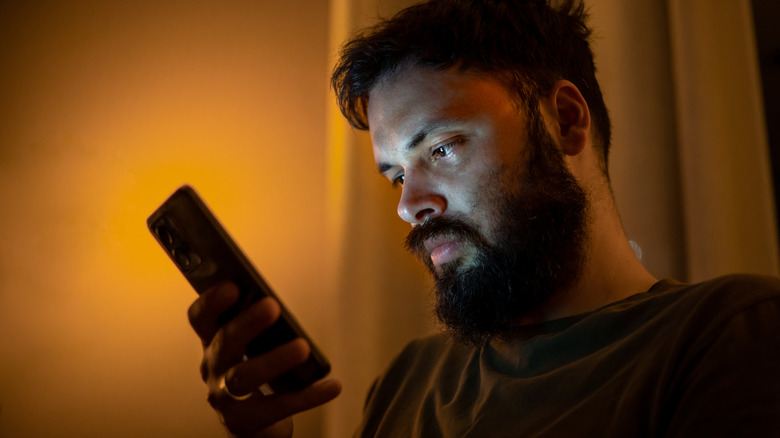 A man looking at a phone at night