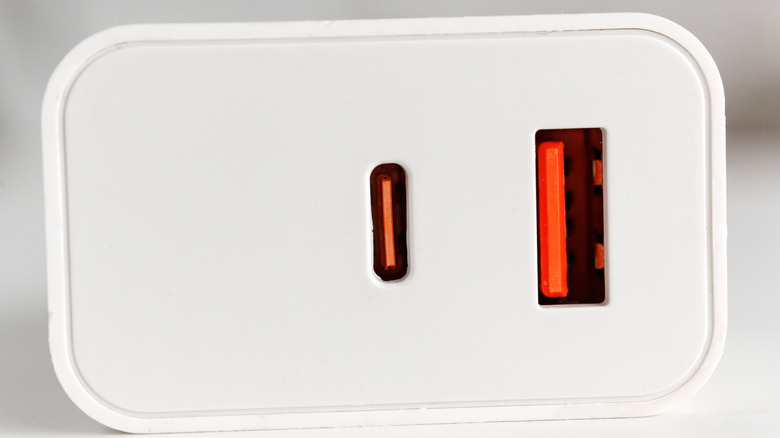 A close-up photograph of a USB charging block showing both an orange USB Type-A port and an orange USB Type-C port.