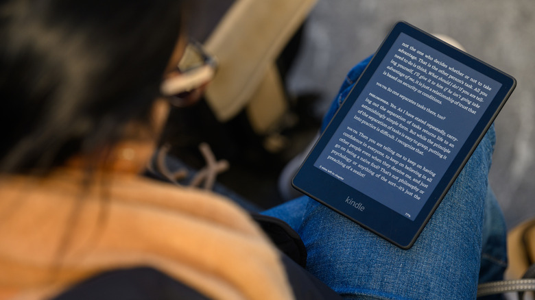 A person reading a Kindle on their lap