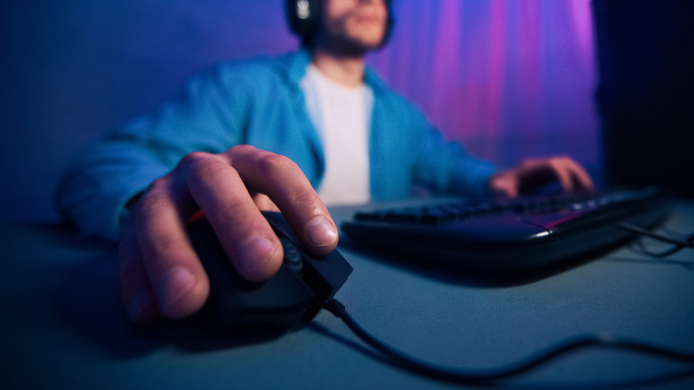 A close-up of a person's hand on a mouse while they're using a keyboard