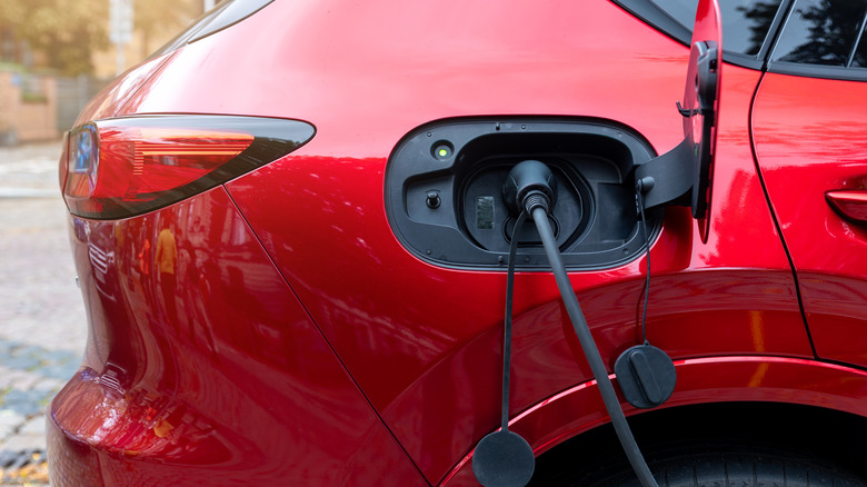 A red hybrid SUV being charged.