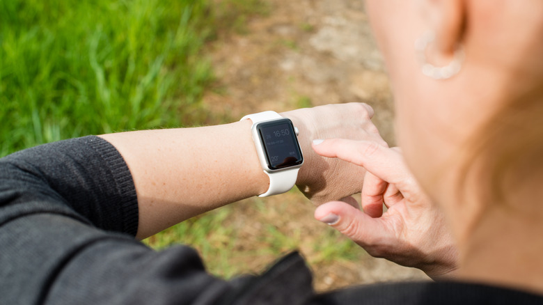 Woman checking her Apple Watch displaying the home screen