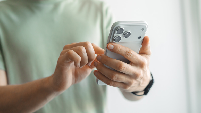 A person holding an iPhone in one hand and using the other to tap on it