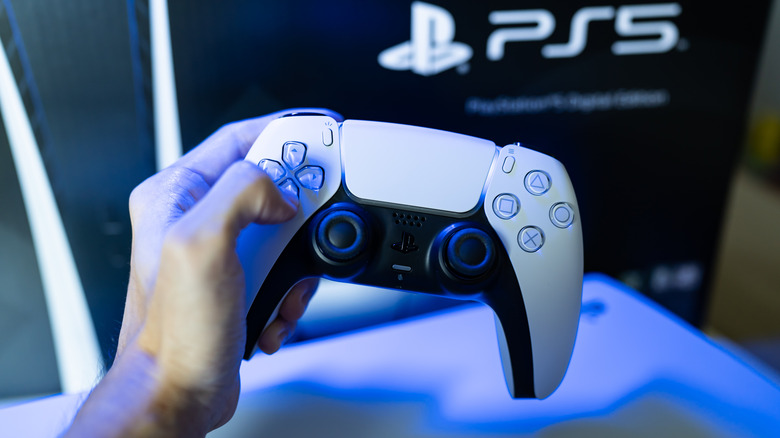 Person holding DualSense controller bathed in blue light