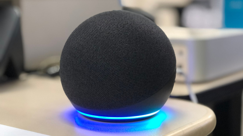 An Amazon Echo speaker on a smooth surface displaying a blue solid light around its base