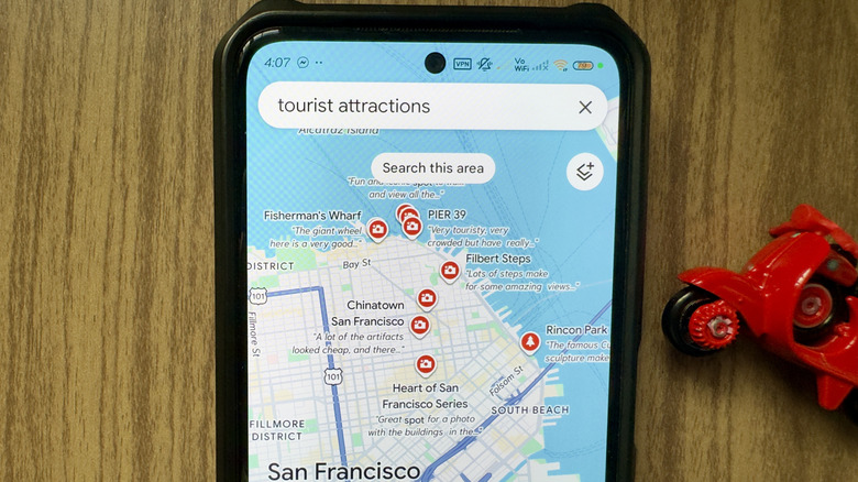 The Google Maps app showing a camera icon on a map loaded on a smartphone against a woodgrain background
