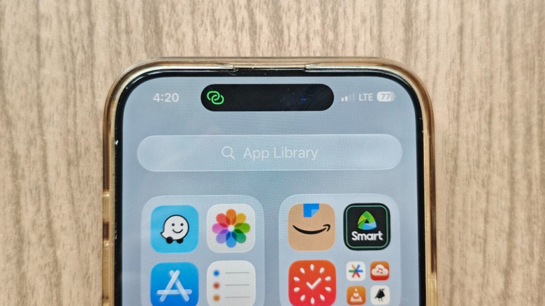 An iPhone showing a green chain link symbol in the Dynamic Island area