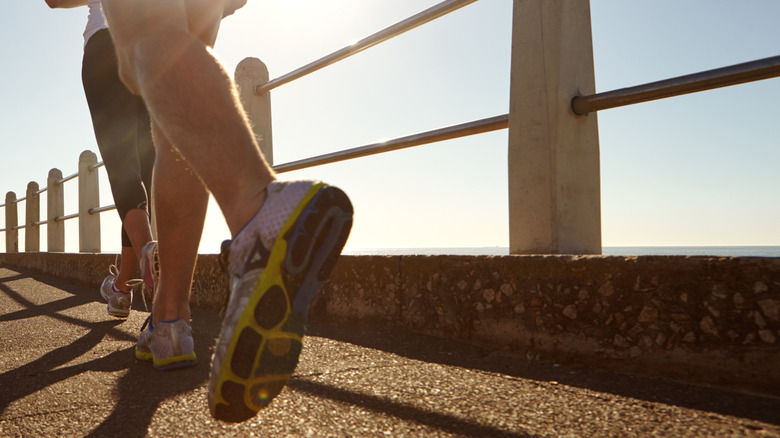 Two people running outdoors on a sunny day.