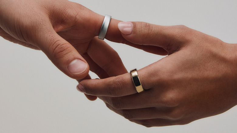 Two hands, each wearing an Oura Ring, against a white background.