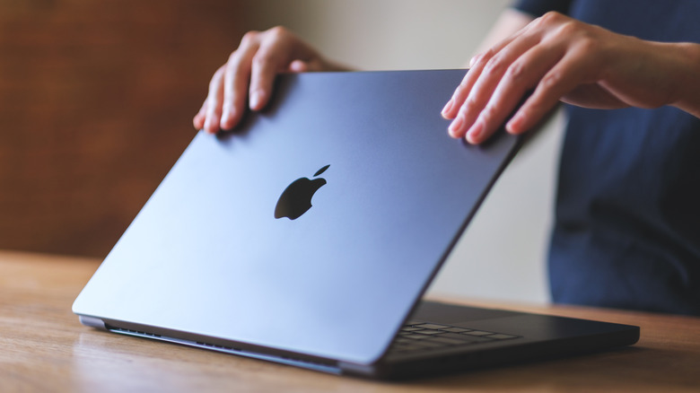 A person opening or closing an Apple MacBook Pro laptop computer,