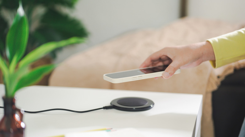 Close-up of a person placing a phone on a wireless charger