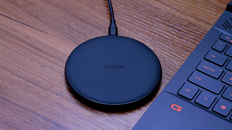An Anker wireless charging pad on a desk beside a laptop