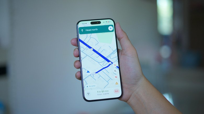 A close-up of a person holding up the Google Maps interface shown on their smartphone.