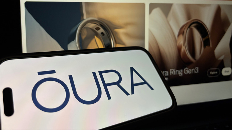 An image of the Oura app on a smart phone in front of a screen displaying some of the smart rings