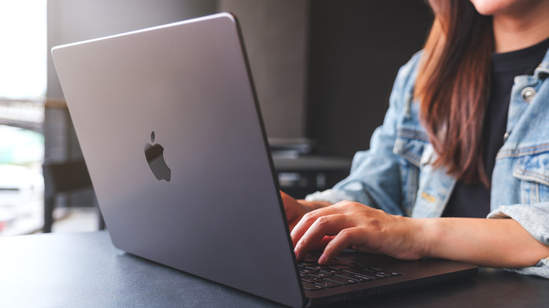 A woman typing on a MacBook.
