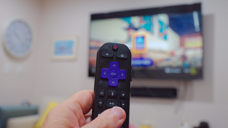 Close up of a Roku remote in front of a TV