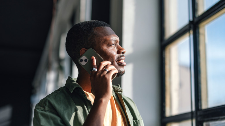 A person talking on the phone while looking out the window.