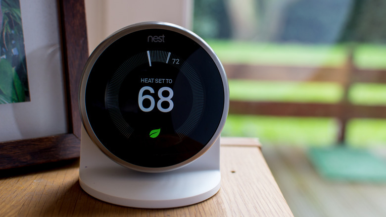 Google Nest thermostat on small stand resting atop a shelf.