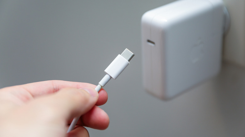 A USB-C cable being plugged into an Apple wall adapter.