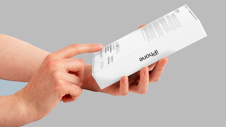 A person checking the back of an iPhone's original box