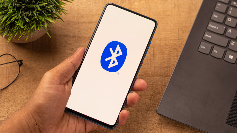 The Bluetooth logo on a smartphone display near a laptop