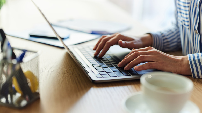 A person typing on a laptop on a desk