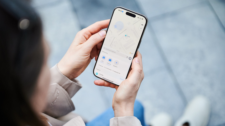 A woman holding an iPhone with the Maps app open.
