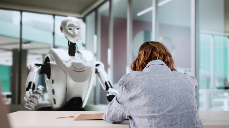 Person near robot in a briefing room.