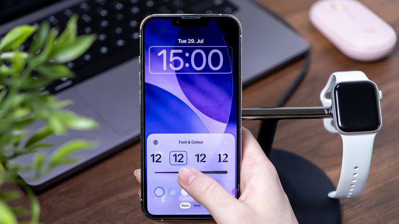 person optimizing the font and color of iPhone's lock screen with an Apple Watch on the side