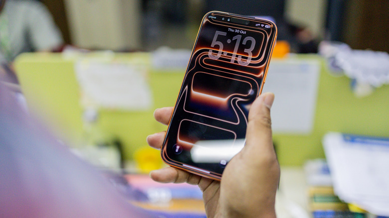 person holding an iPhone 17 Pro Max in an office setup