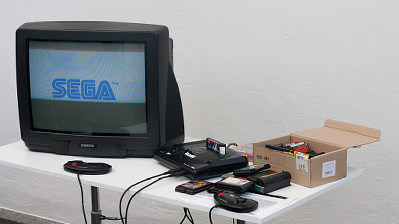 Old-school Sega console with games and TV on table