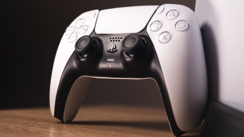 A closeup of a white DualSense controller propped up against a PS5