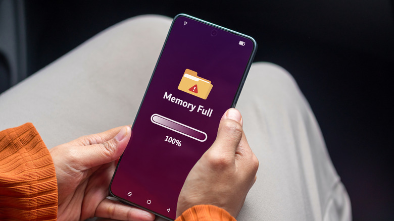 A person holding a smartphone with a full memory notification.