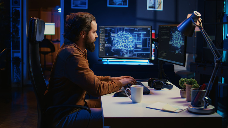 computer scientist working at a computer desk with two monitors