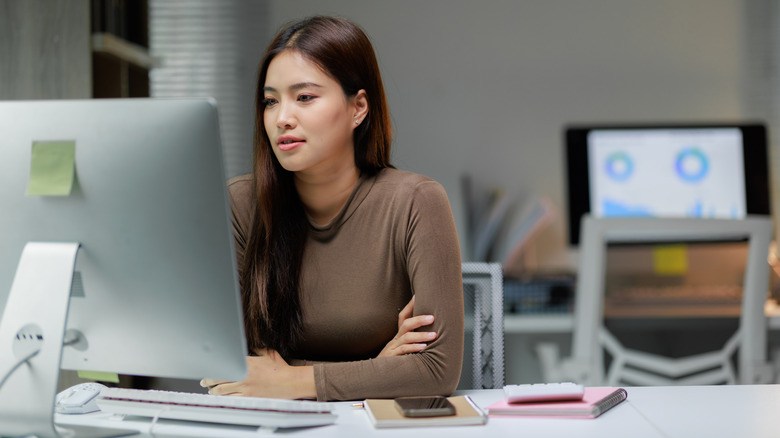 woman in front of a large monitor in an office workspace