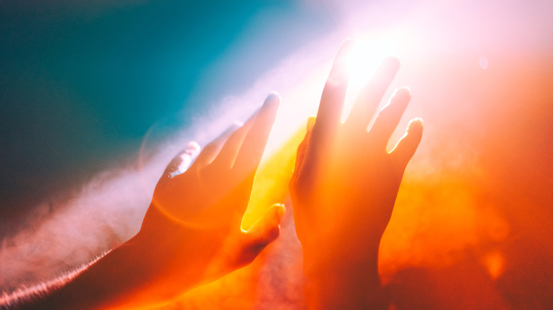 two hands help up toward bright light