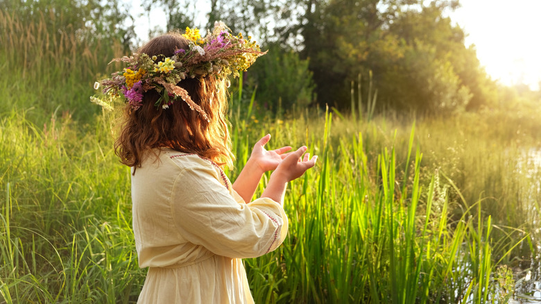 pagan girl with a flower wreath connecting with nature spiritually