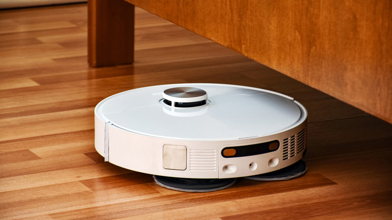 a robot vacuum cleaning up under a bed