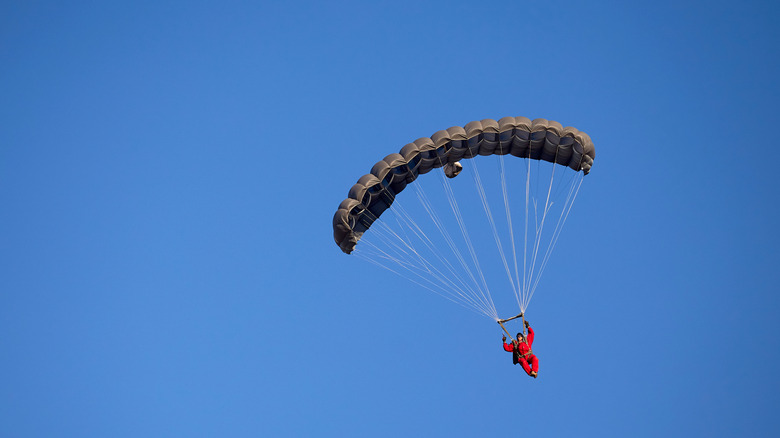 Paratrooper descending from sky with parachute