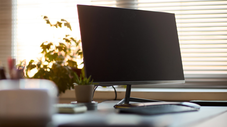 Computer monitor on a desk with the screen off.