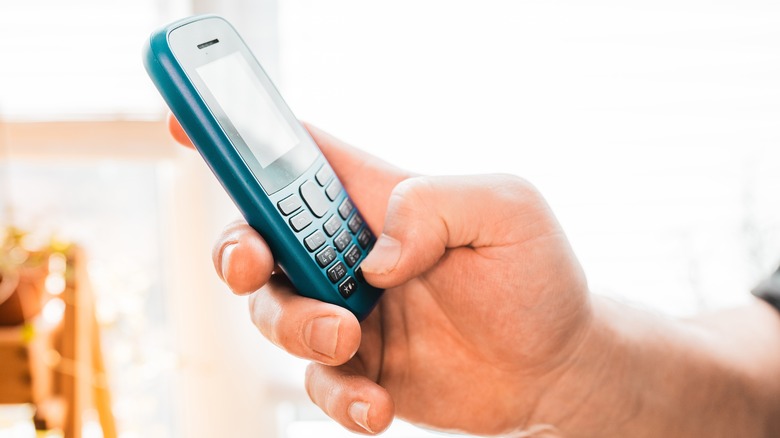 A man holding an old dumbphone.