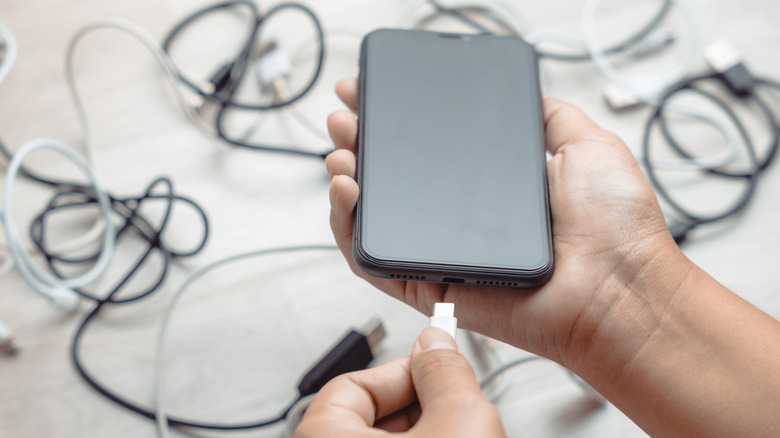 A person connecting a USB cable to a smartphone.