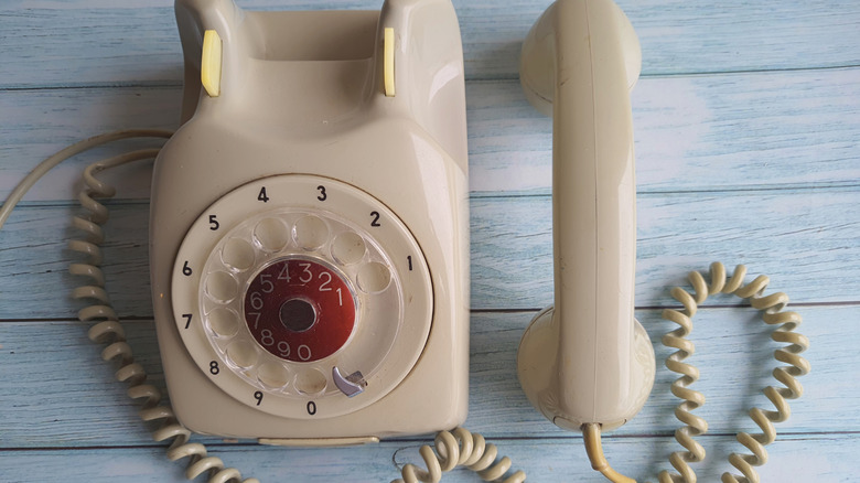 Old rotary phone on wooden surface from above.