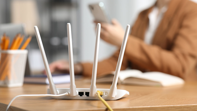 A wireless router in the foreground plugged into ethernet and power.