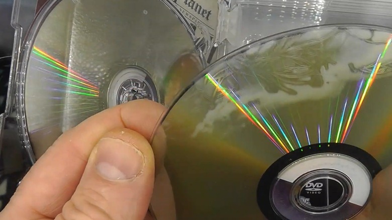 Person holding a DVD with milky staining and disc rot