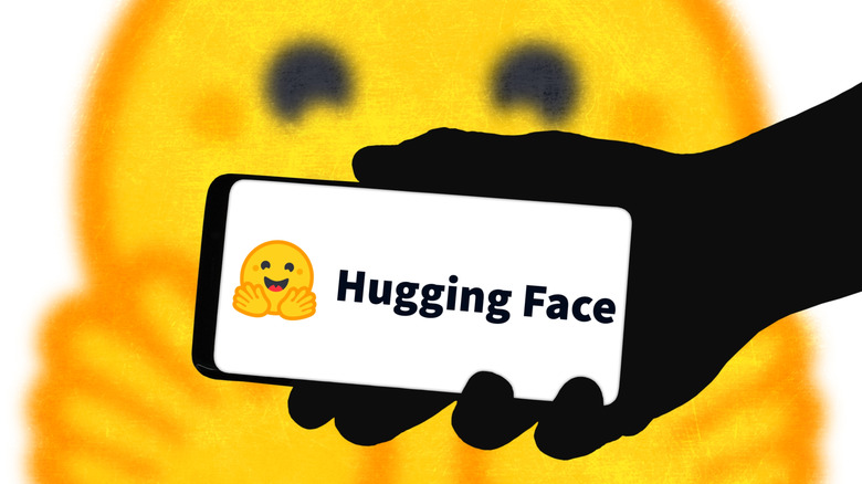 Person holding phone with Hugging Face logo in front of a hugging face emoji.