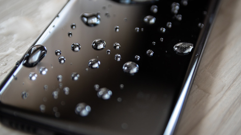 Smartphone display covered in drops of water.