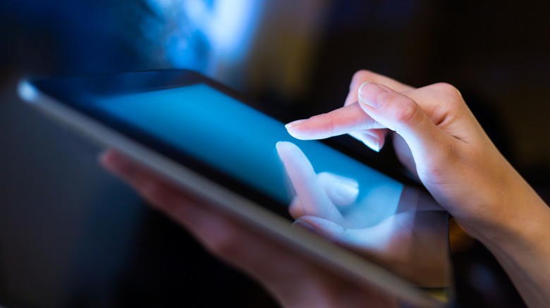 Finger about to press on tablet touchscreen.
