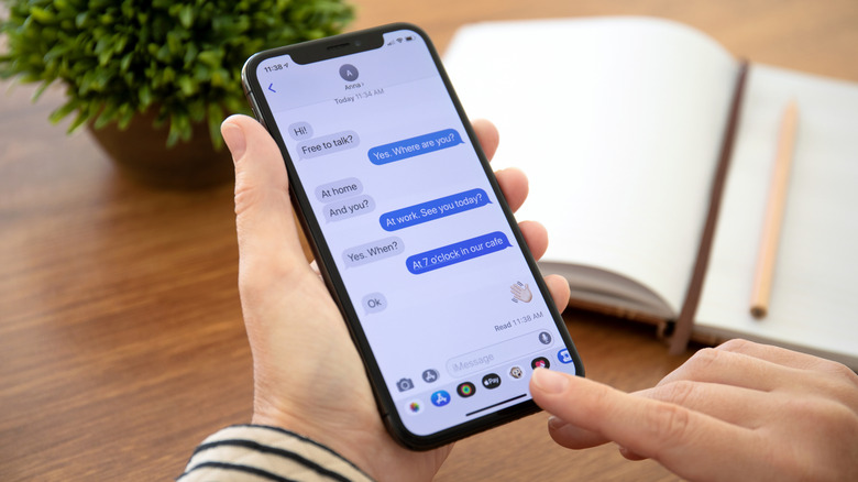 Someone holding an iPhone and reading a text in iMessage.